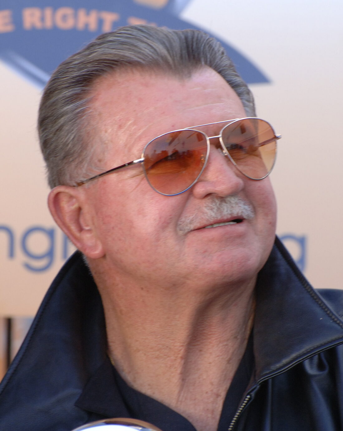 Mike Ditka in aviator sunglasses and a leather jacket at the 2008 NFL Experience, the Chicago Bears legend whose sports figure death at 86 was confirmed in October 2026