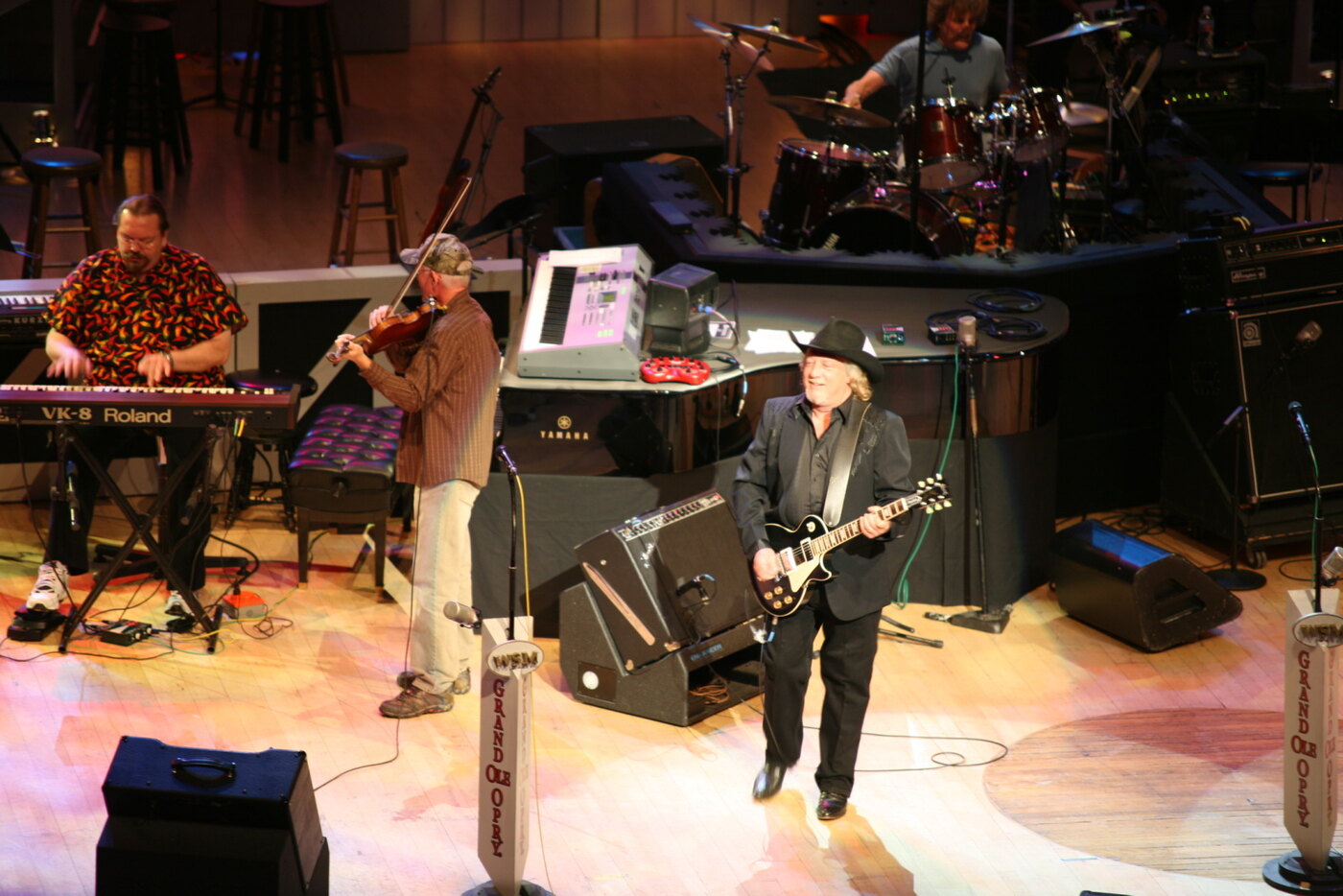 John Anderson performing on the Grand Ole Opry stage in 2007 with fiddle and keyboard players behind him, nineteen years before the celebrity death of the Seminole Wind singer